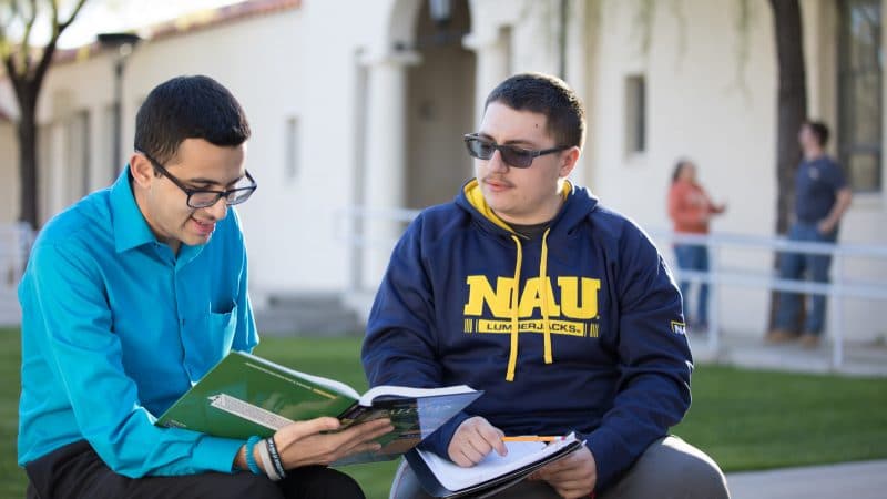 Students discussing a book outside.