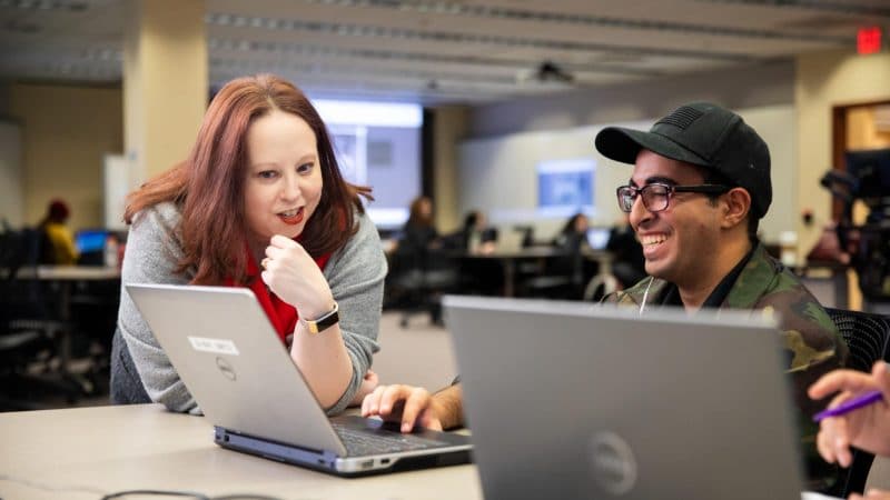 A professor helping a student on his laptop.