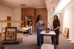 Students work in a museum gallery examining the condition of objects.