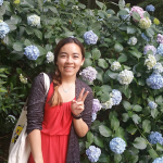 NAU student posing in front of a flower bush.