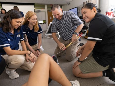 Athletic trainers kneeling on the floor.