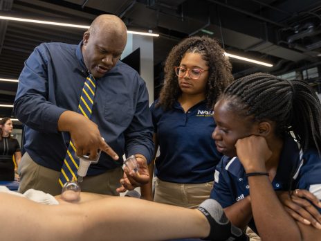 Professor shows two students how to provide therapy.