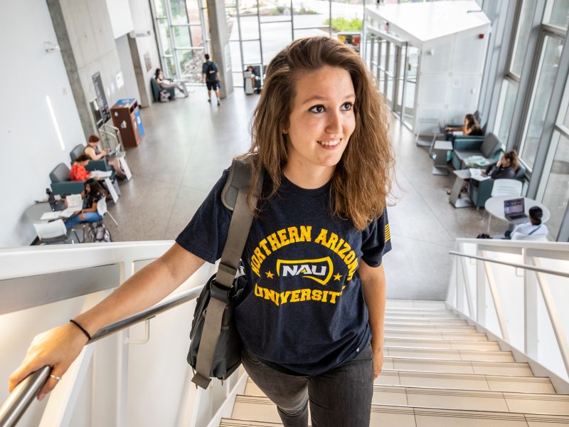 Student with a backpack going upstairs.