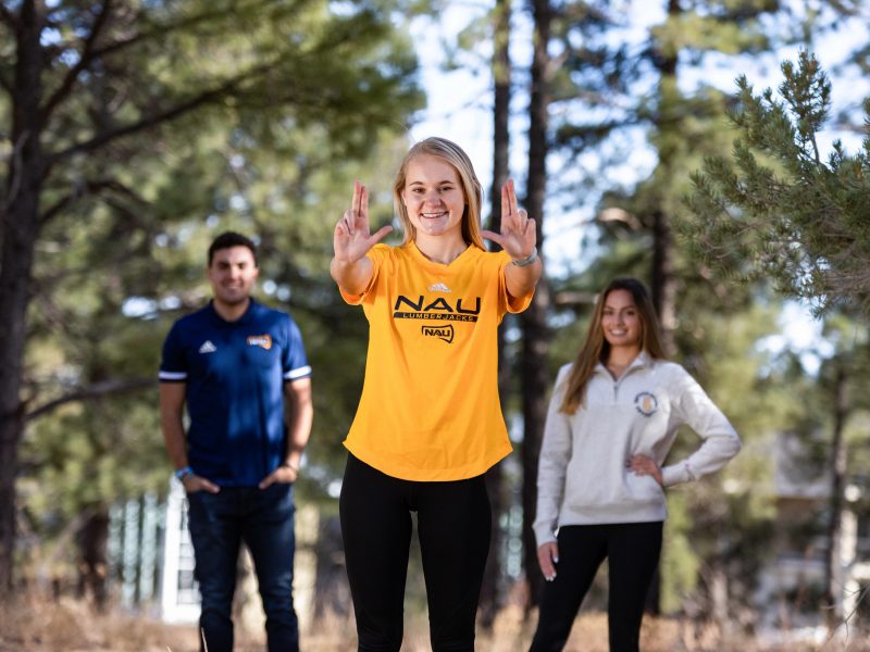 A photo of students wearing N A U shirts posing with the "Lumberjacks" sign.