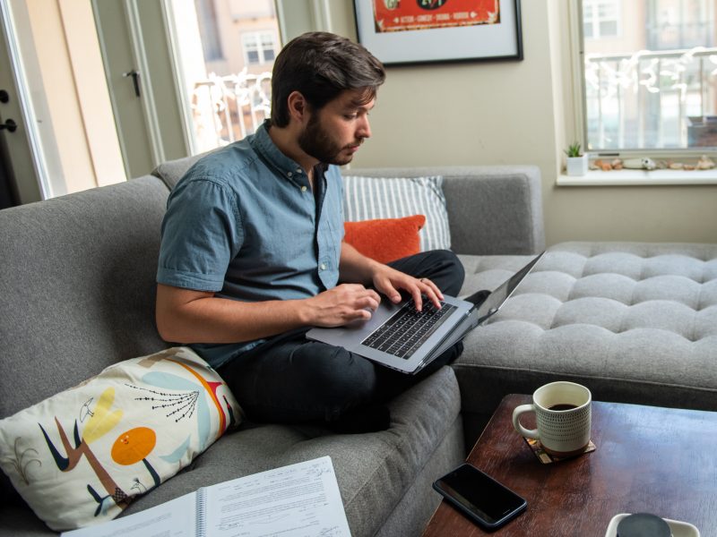 Student studies on laptop while sitting on couch.
