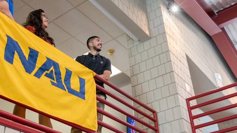 Students standing and smiling next to a N A U–Yuma banner.